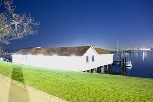 Panoramic view of grassy field next to commercial buildings under blue sky.