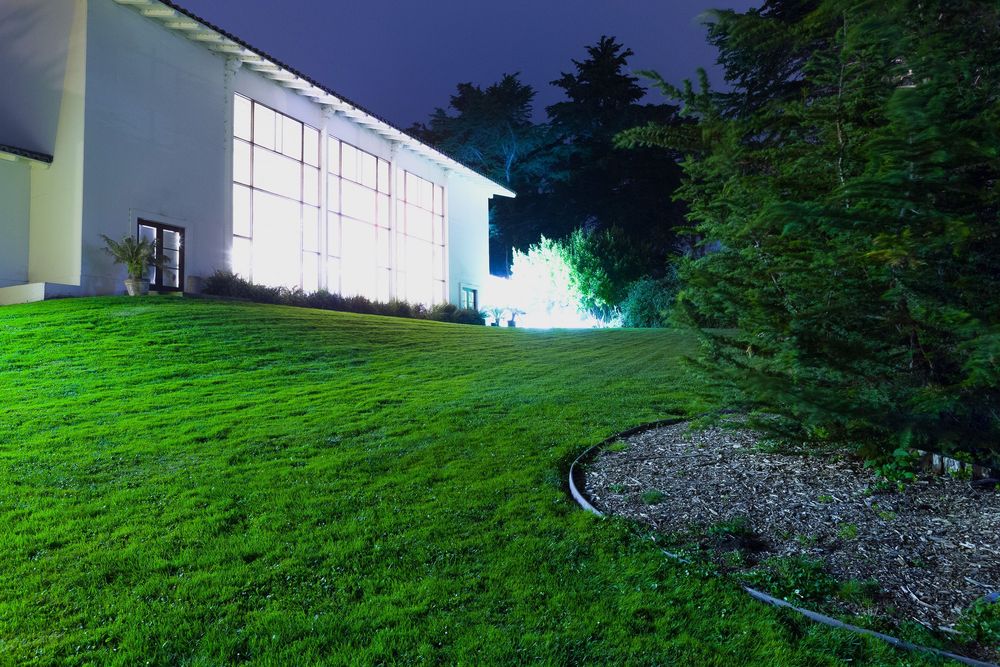 Sloping green lawn beside white building structures at twilight.