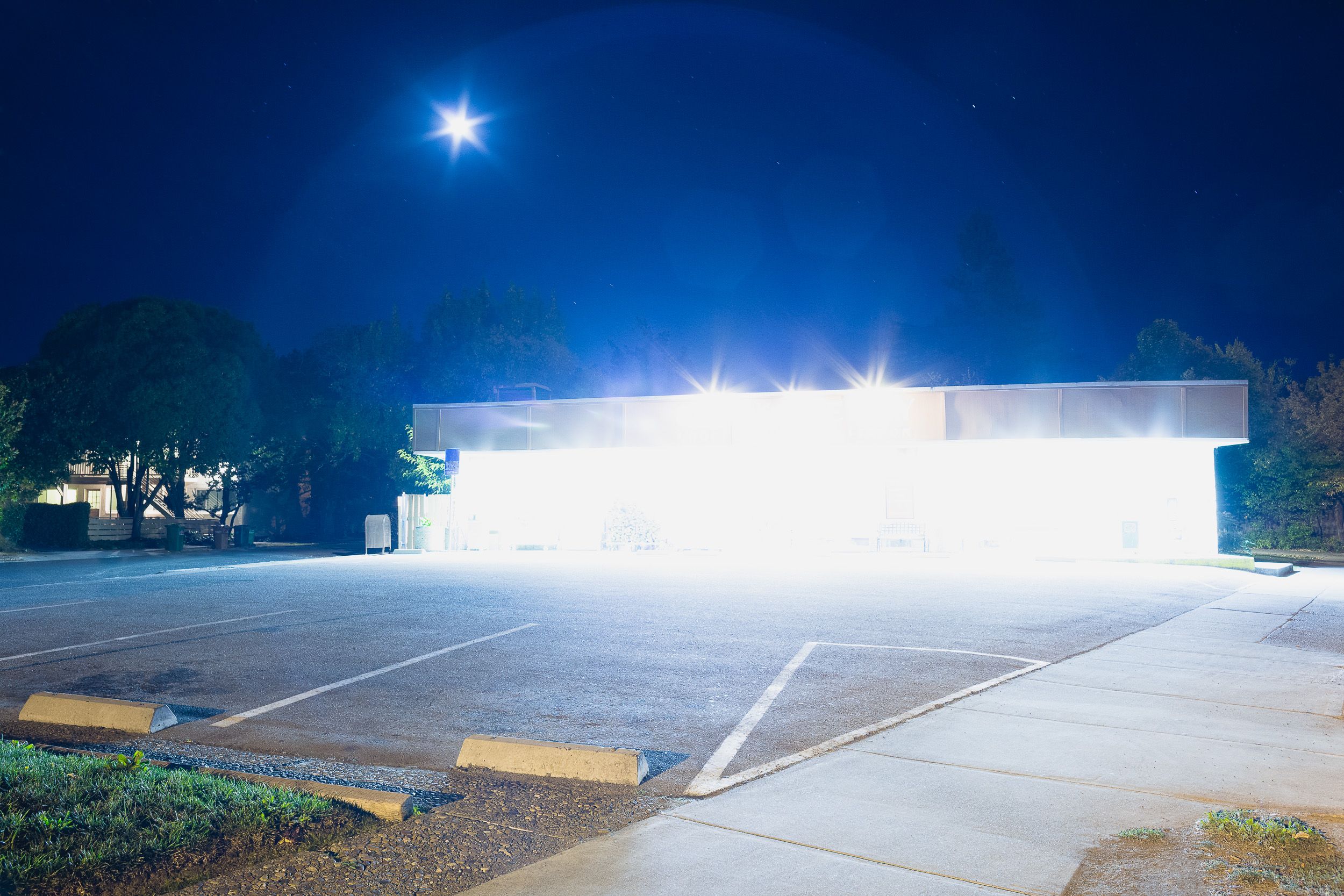 Empty parking lot with bright security lights creating dramatic nighttime shadows.