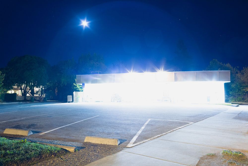 Empty parking lot with bright security lights creating dramatic nighttime shadows.
