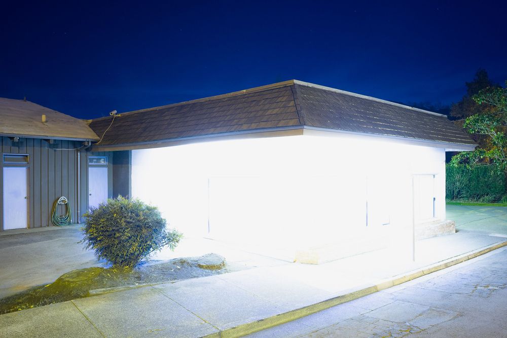Long exposure shot of white building exterior with bright security lighting at night.