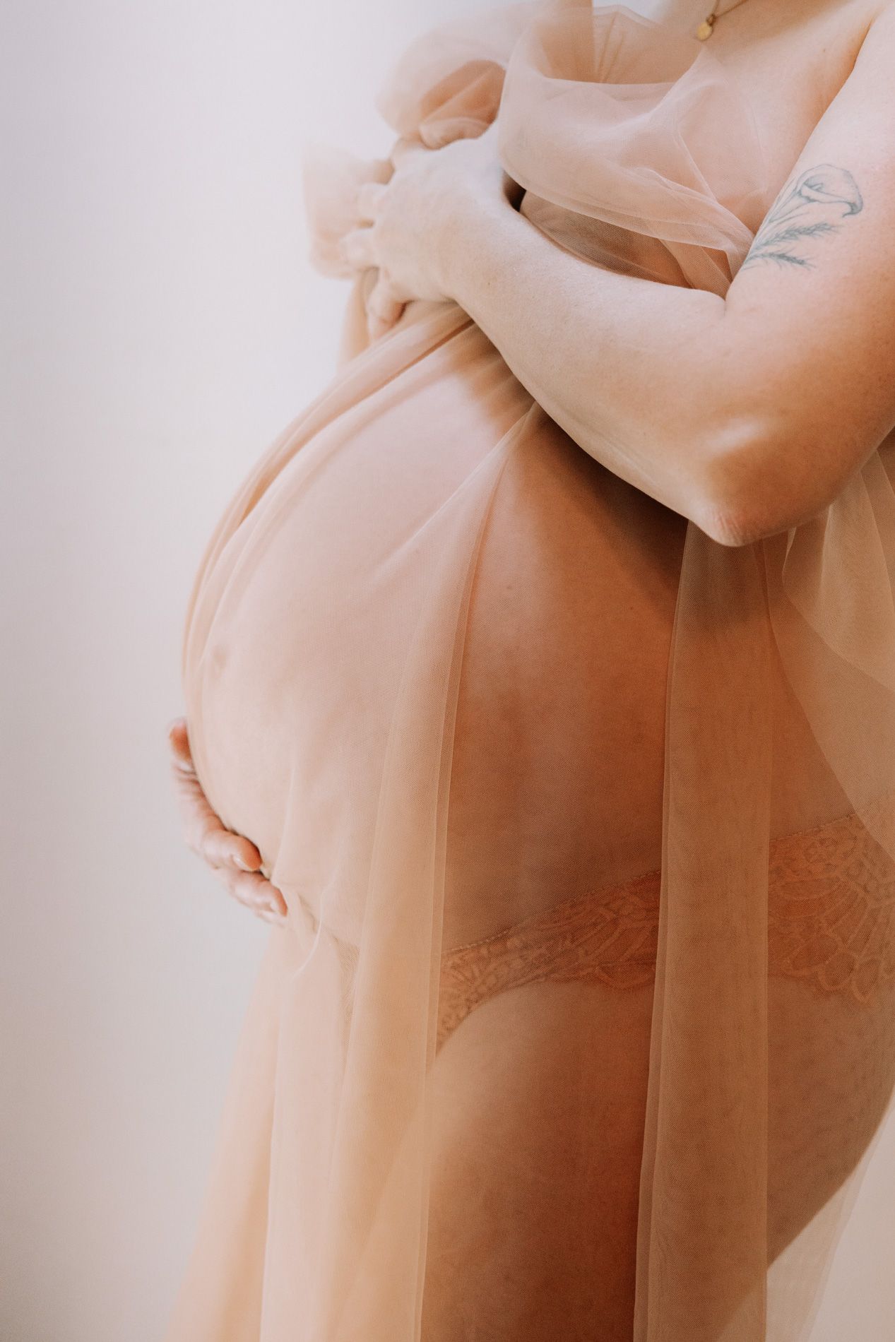 A soft and dreamy maternity photo featuring a silhouette of a pregnant figure in gentle lighting.