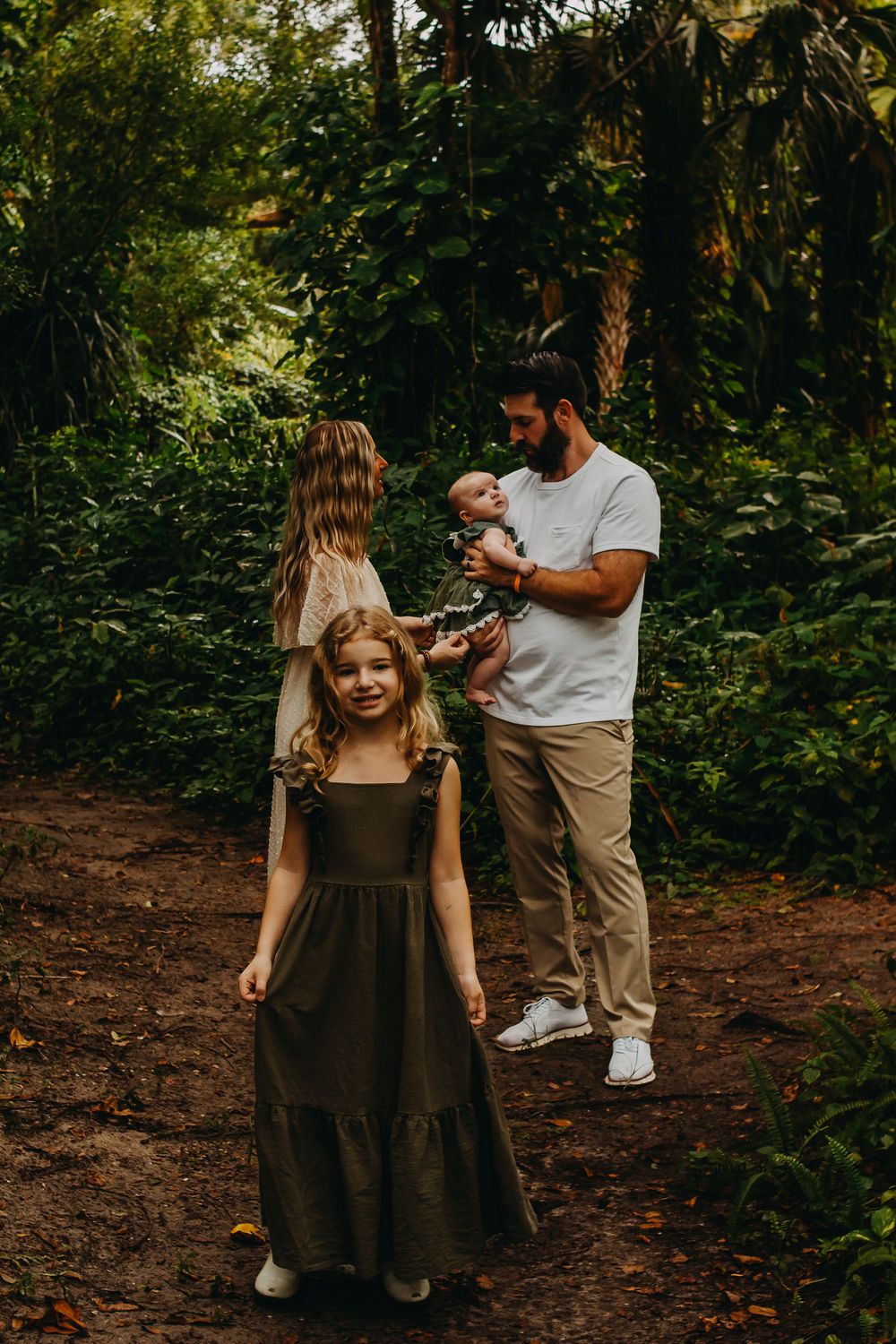 A family enjoying a tender moment together on a wooded path surrounded by lush greenery.