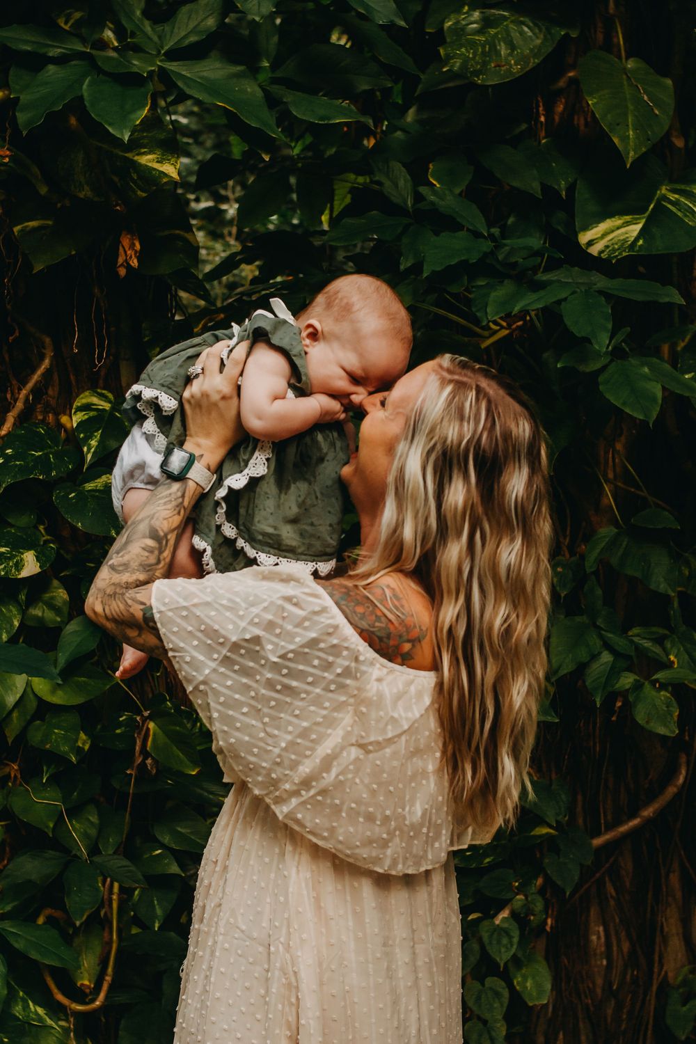 A tender moment between parent and baby against a backdrop of green foliage.