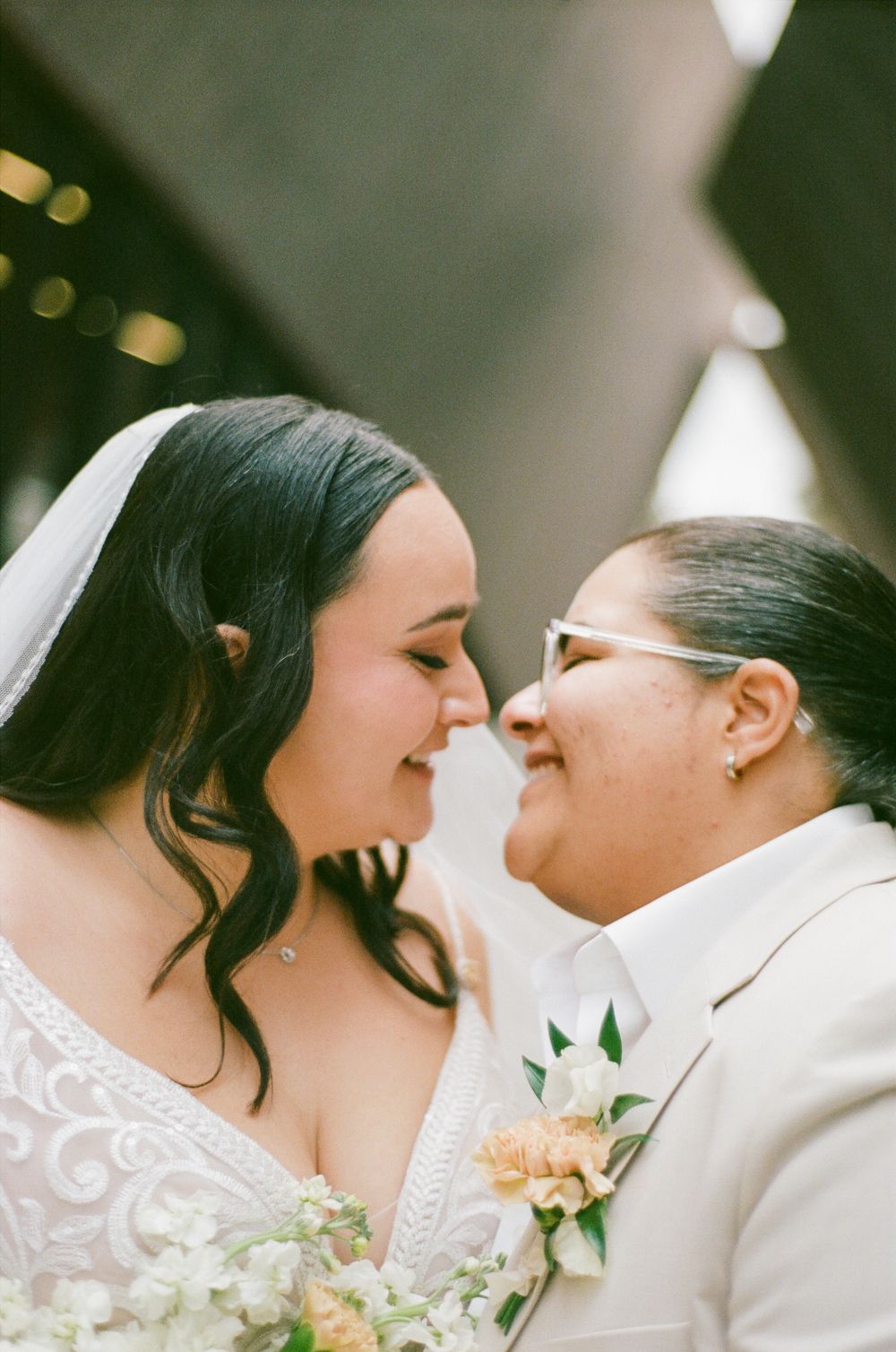 A romantic wedding moment captured in soft focus with peach flowers and white floral lace details.