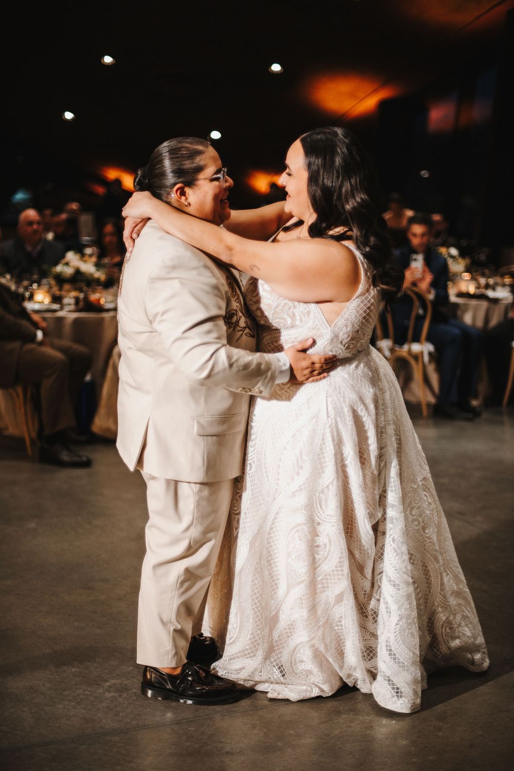 A couple in wedding attire share an intimate moment during their first dance at their reception.