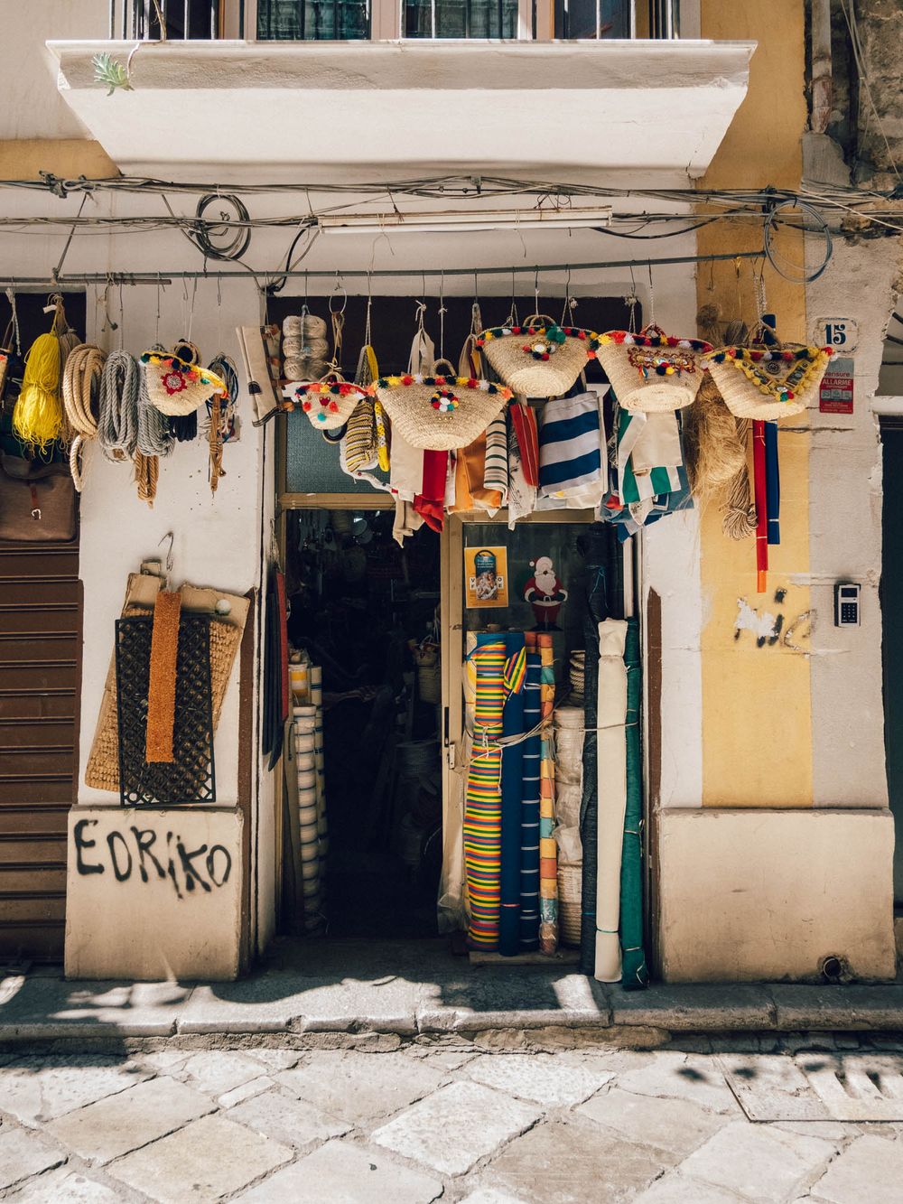 A series of colorful storefronts in Havana with hanging laundry, graffiti, and vintage architectural details.