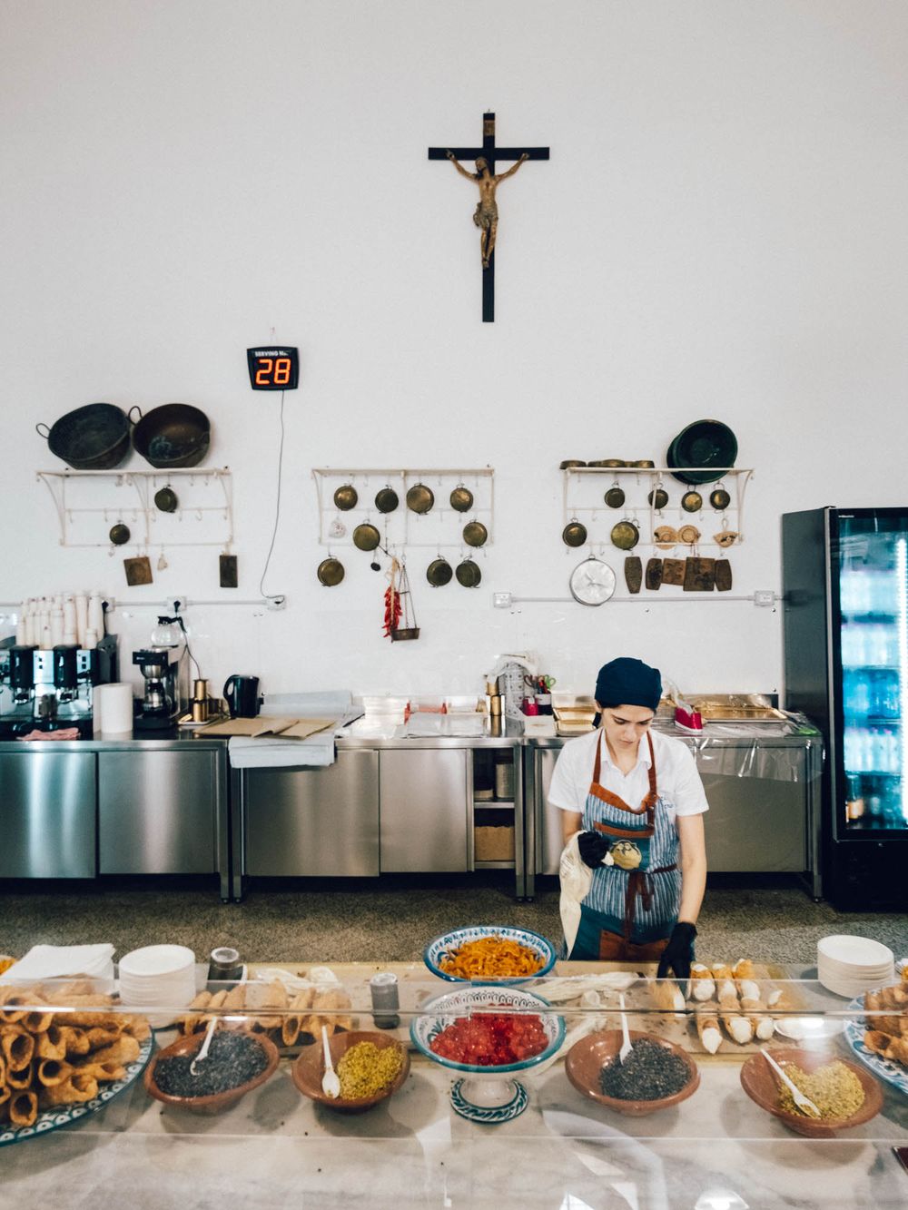 A buffet line setup in a commercial kitchen displays various dishes and ingredients spread across a stainless steel counter.