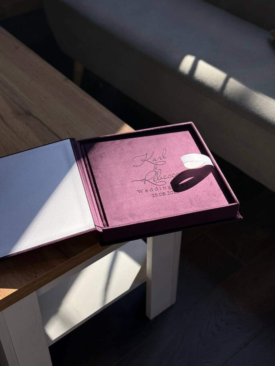 Pink notebook or diary casting dramatic shadows on a white surface in minimalist lighting conditions.
