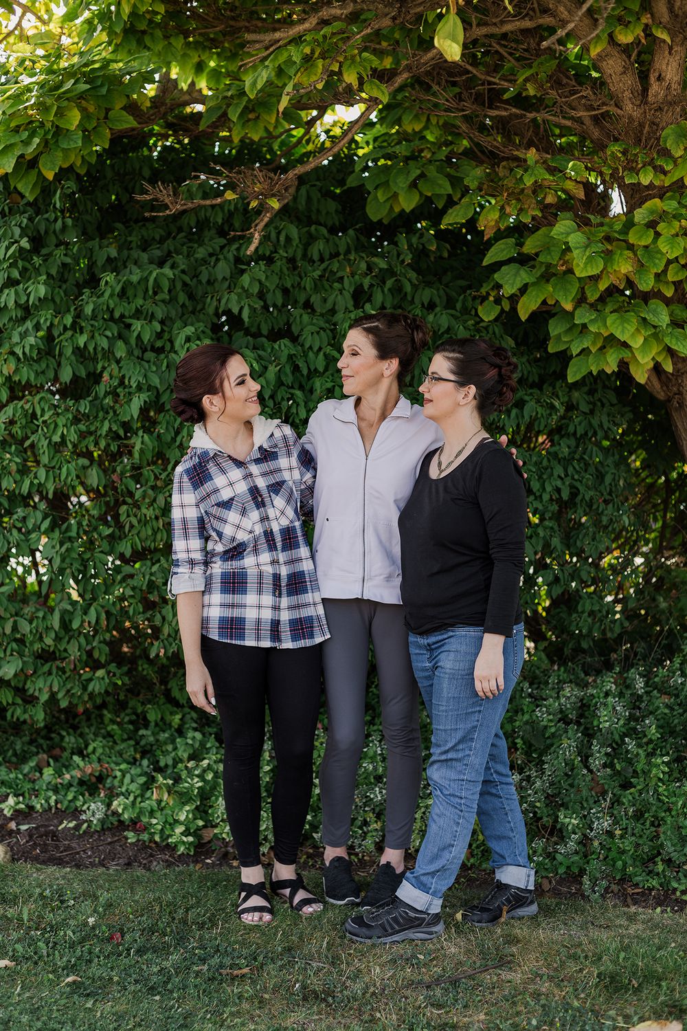 Bride with her mom and sister in front of some greenery in the morning in Kitchener, Ontario.