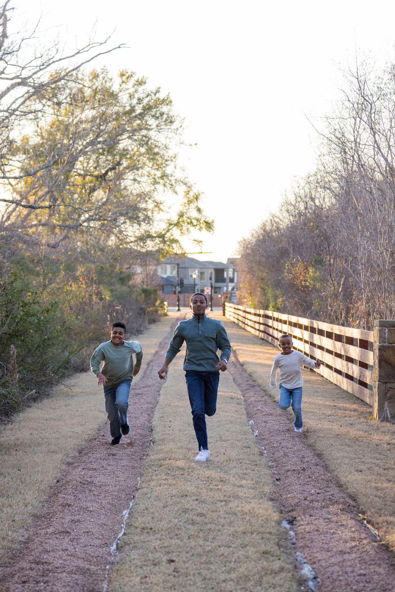 A family walks together on a wooden boardwalk path through a natural area during golden hour.