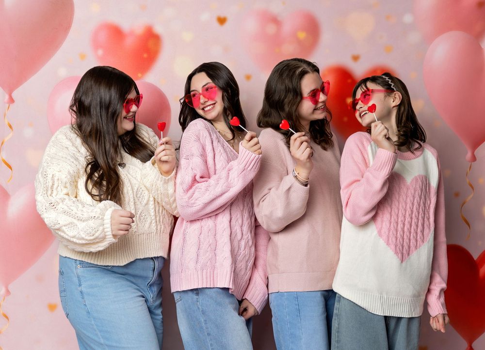 Group of teen best friends pose together on pink heart backdrop during Valentine’s studio session in NH