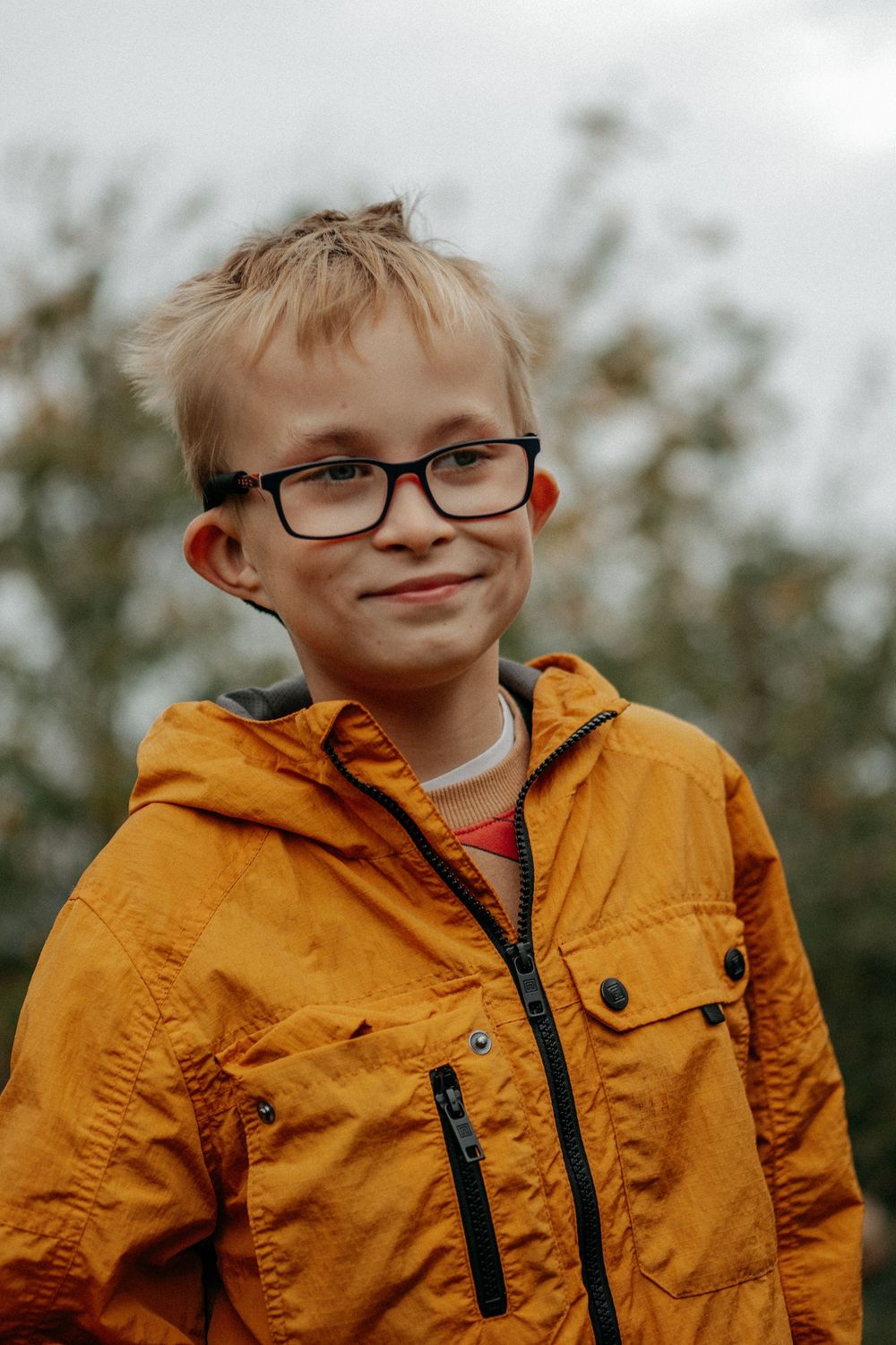 A smiling portrait of a child with an ultra rare genetic condition, wearing a bright yellow raincoat