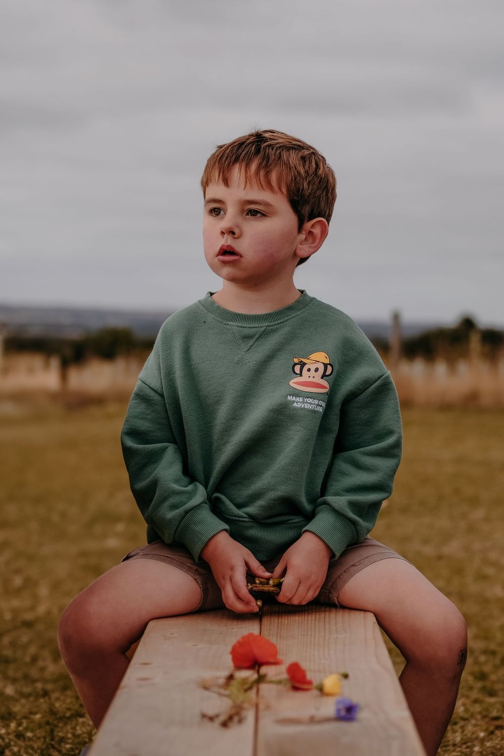 A boy with a rare genetic condition sits on a bench in a field of flowers