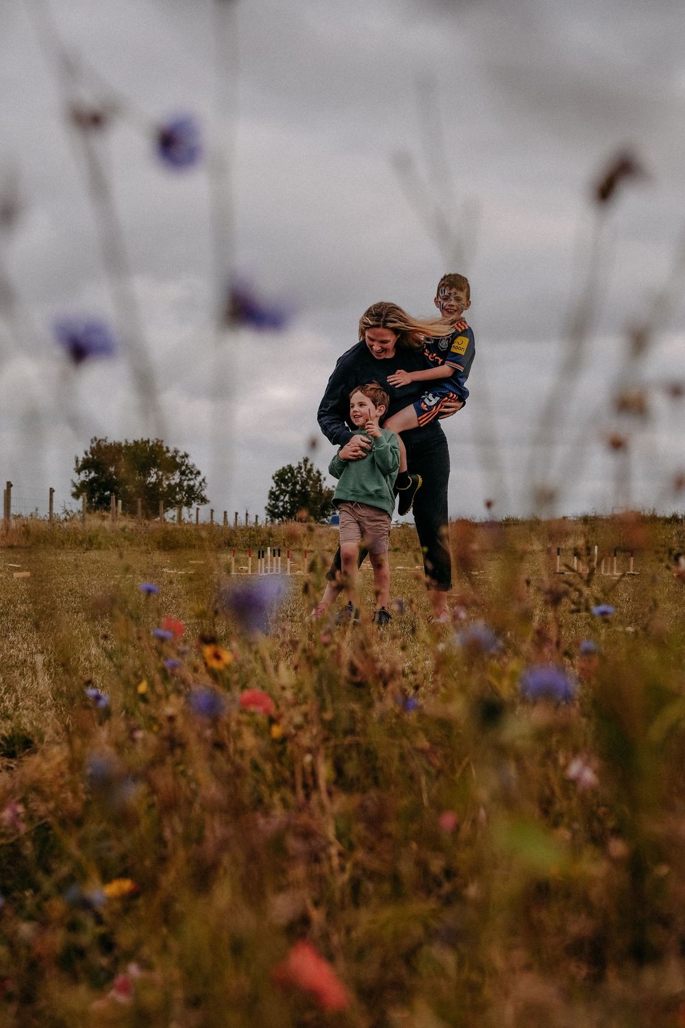 A SEND mom holding her two autistic sons in a field of flowers