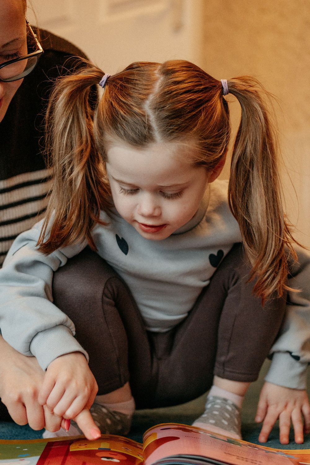 A sweet moment of communcation shared between a mom and her autistic daughter as they read a book in their  family photoshoot in Whitley bay