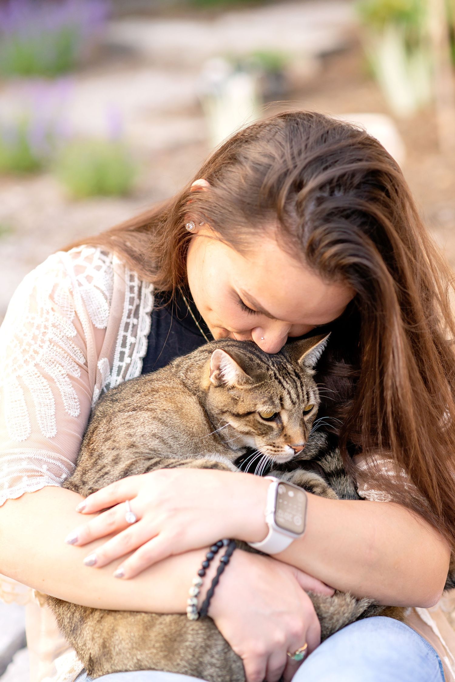 A woman in pink embraces a brown tabby cat in a series of affectionate poses outdoors.