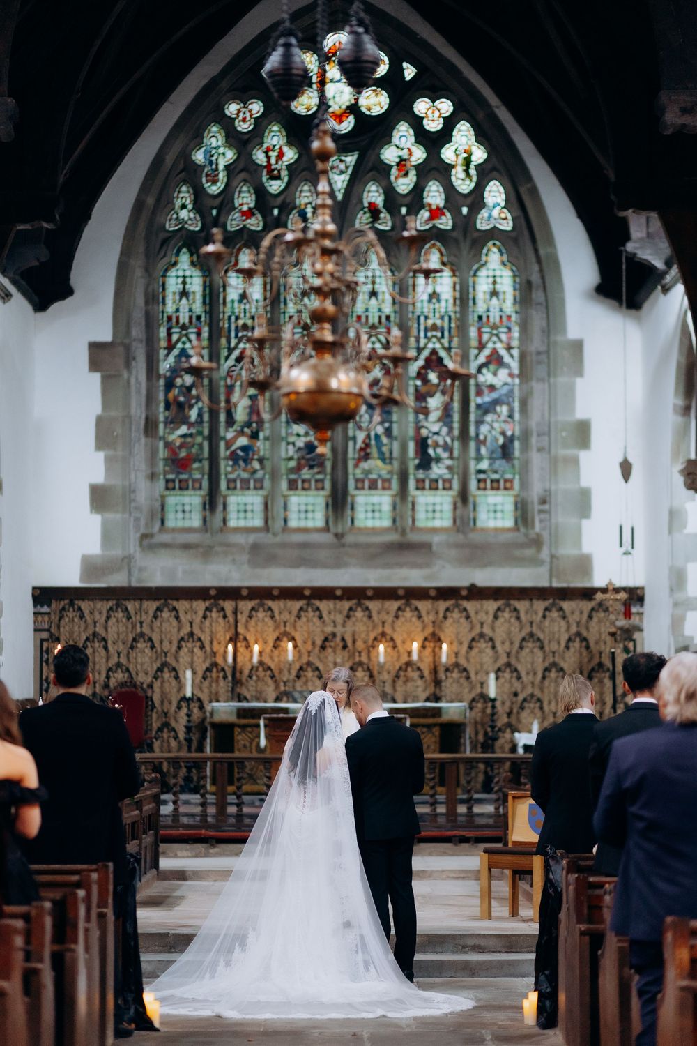 A wedding ceremony in a historic church with beautiful stained glass windows and ornate wooden pews.
