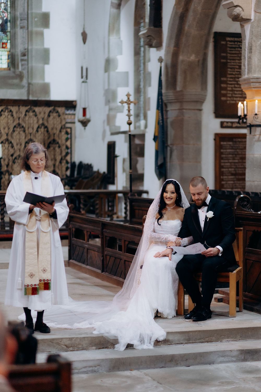 Wedding ceremony taking place on stone steps inside a traditional church with gothic architecture.