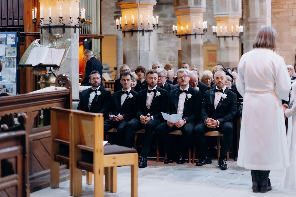 Wedding ceremony in a traditional church with wooden pews and guests in formal attire.