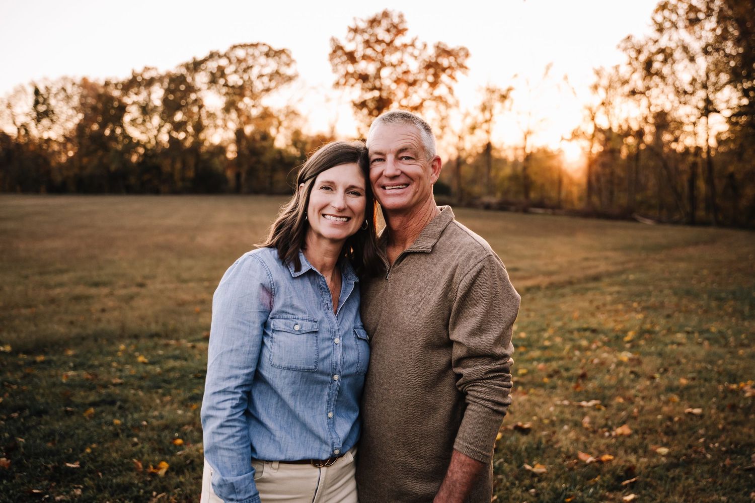 A family shares joyful moments together on a forest path during autumn with golden foliage in the background. Family photographer in Middle