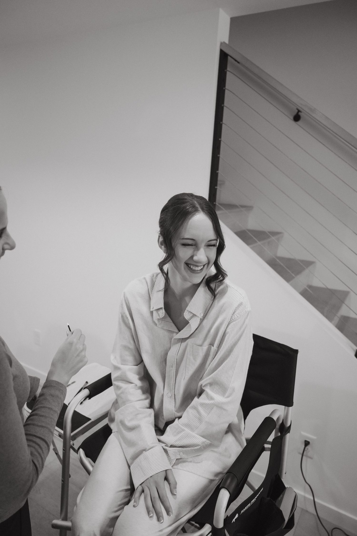 A series of black and white photos showing someone in a white shirt sitting and laughing joyfully in a chair.
