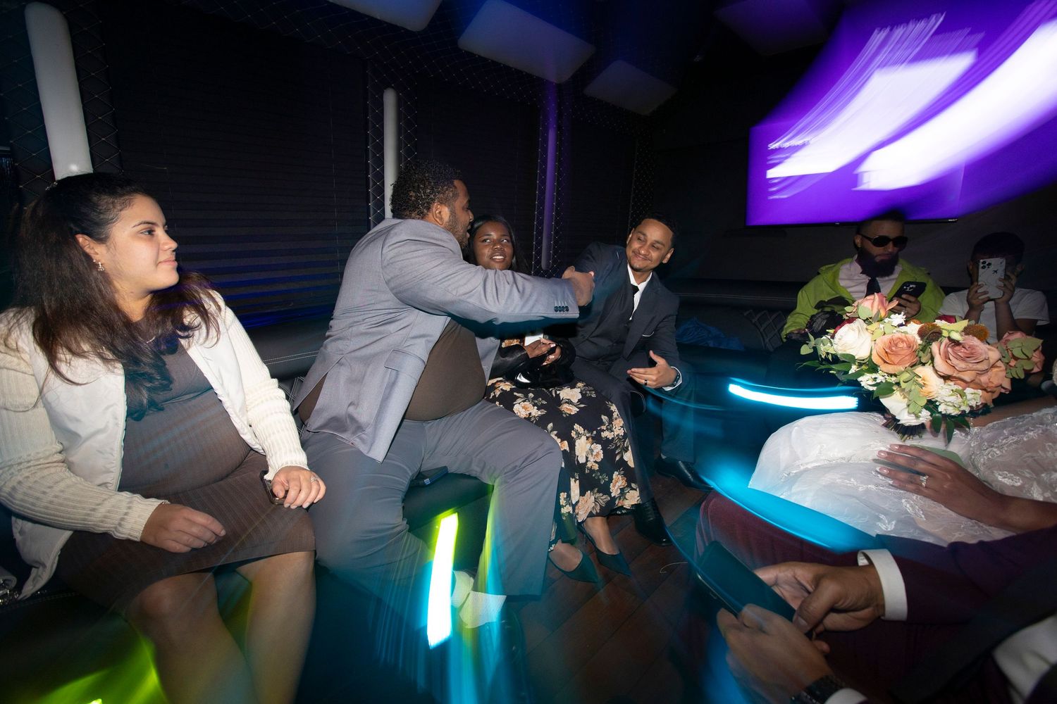 People dancing and socializing at a nighttime event with blue lighting and floral decorations.
