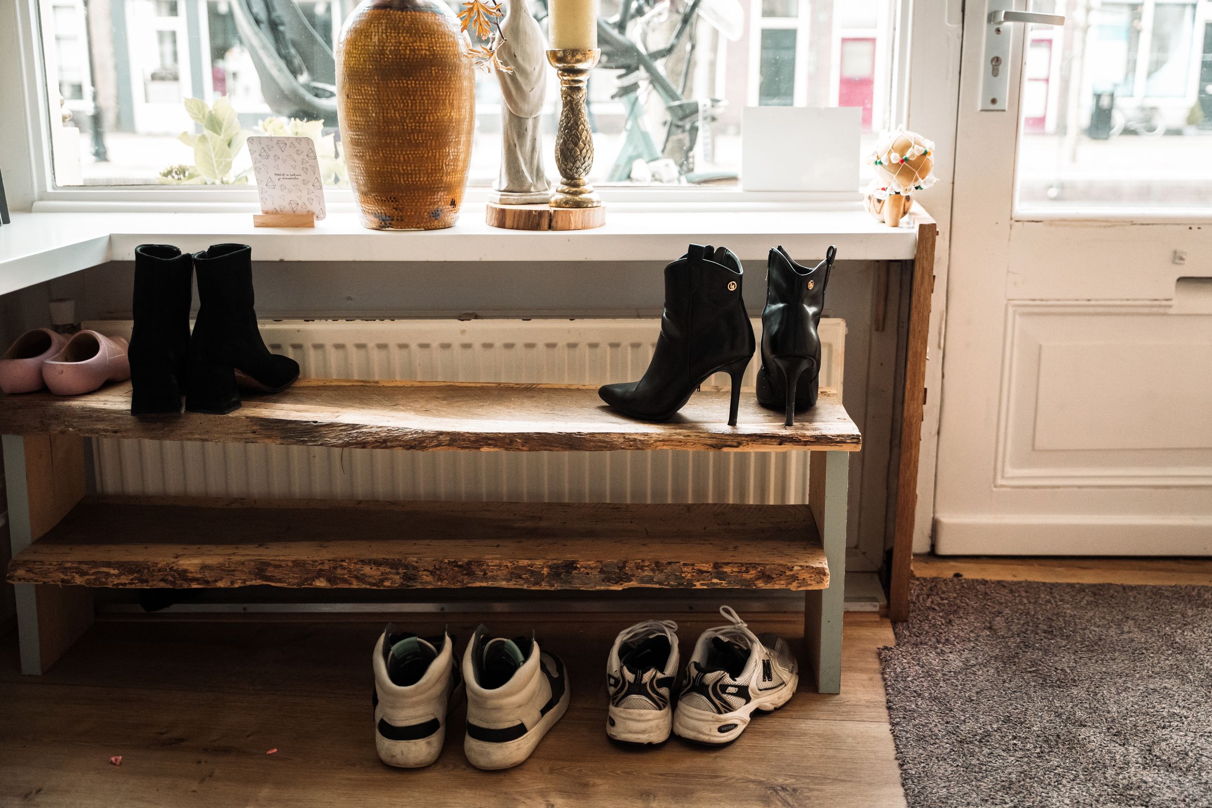 A collection of sneakers and shoes arranged neatly along a windowsill with natural light streaming in.