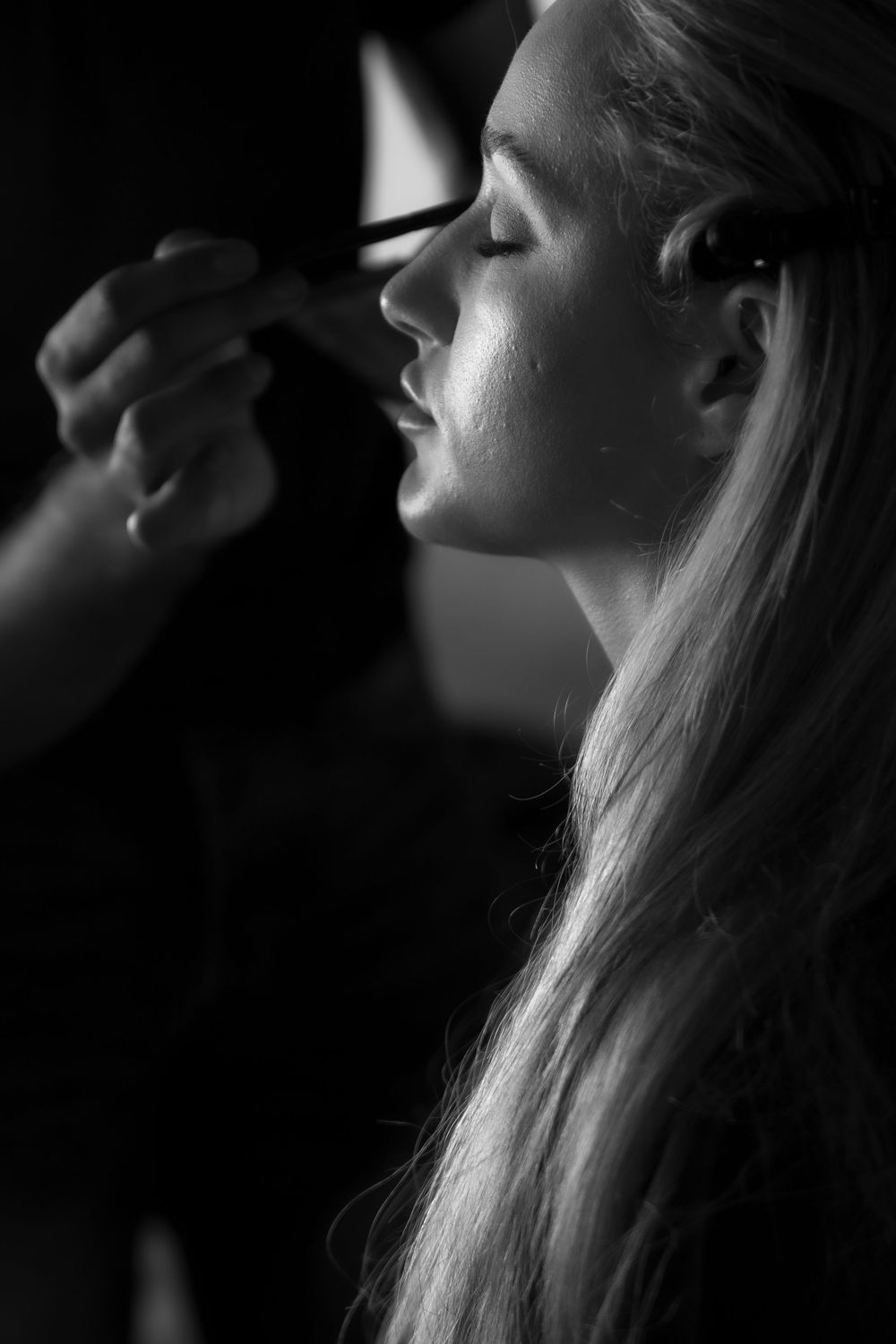 A series of black and white profile portraits showing long hair silhouettes against a dark background.
