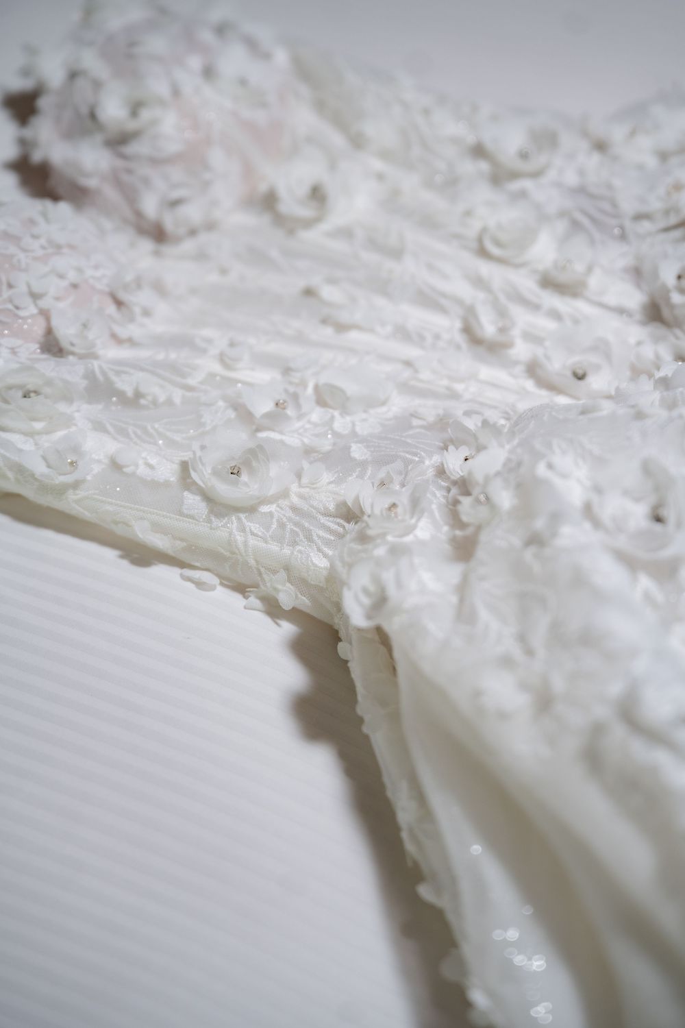 Close up detail of delicate white lace and beading on a wedding dress.