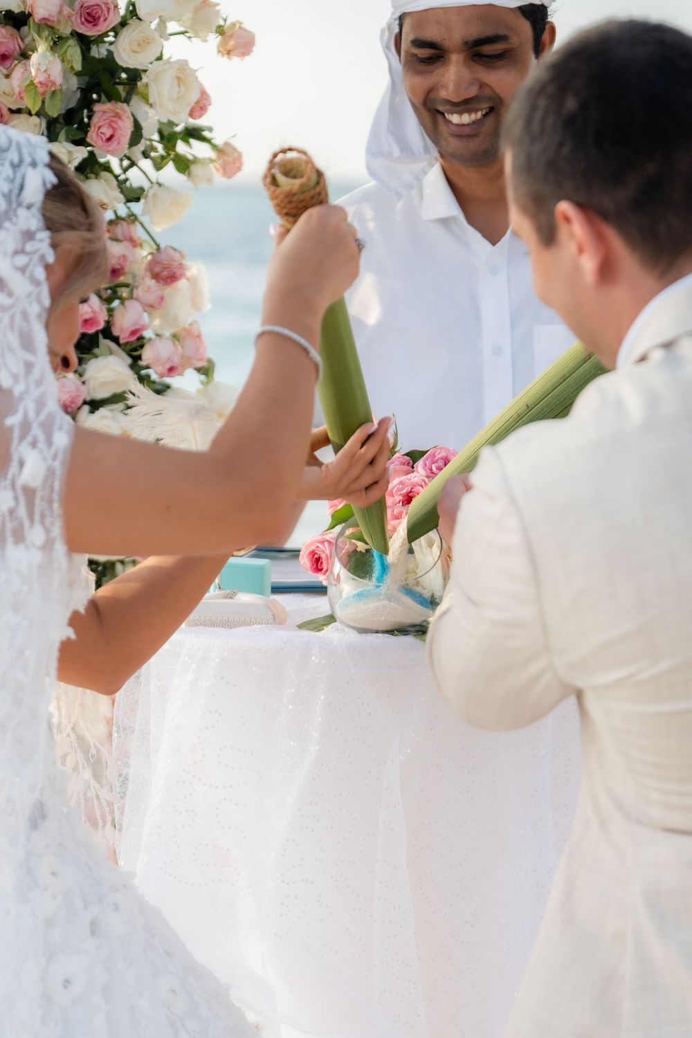 Wedding reception detail showing floral centerpiece and guests sharing dessert at an oceanside venue.