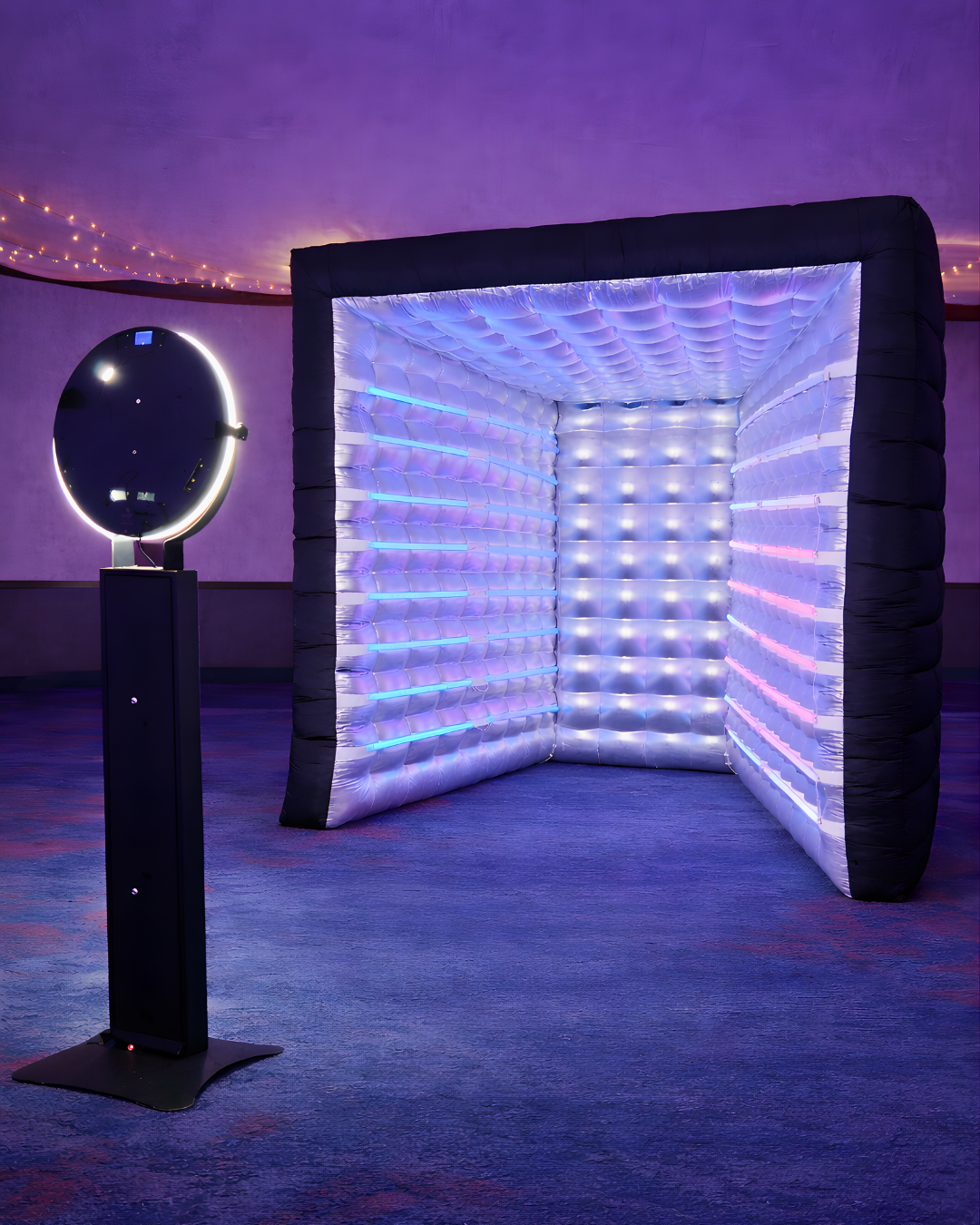 Futuristic art installation with illuminated LED cube booth and circular display stand glowing in purple and blue lighting.