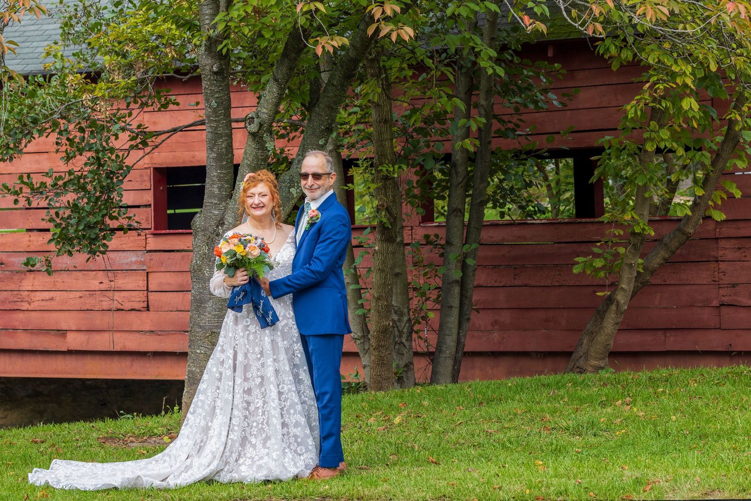 frederick county wedding photography Couple embraces near a rustic red barn during an autumn wedding photoshoot.
