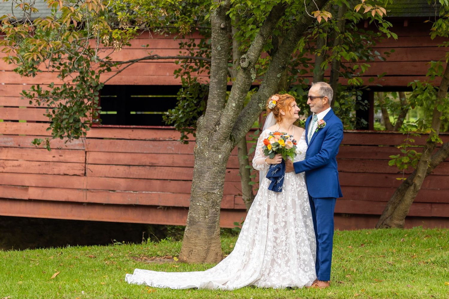 frederick county wedding photography Couple shares romantic moments near a red barn during autumn wedding photography.