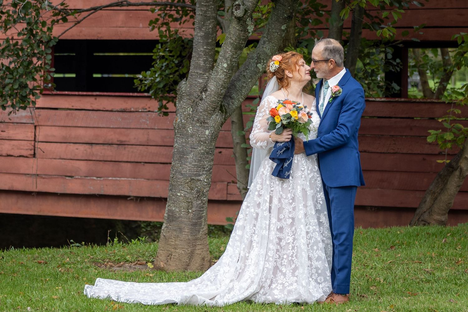 frederick county wedding photography Wedding couple poses for romantic photos near a rustic red barn structure.