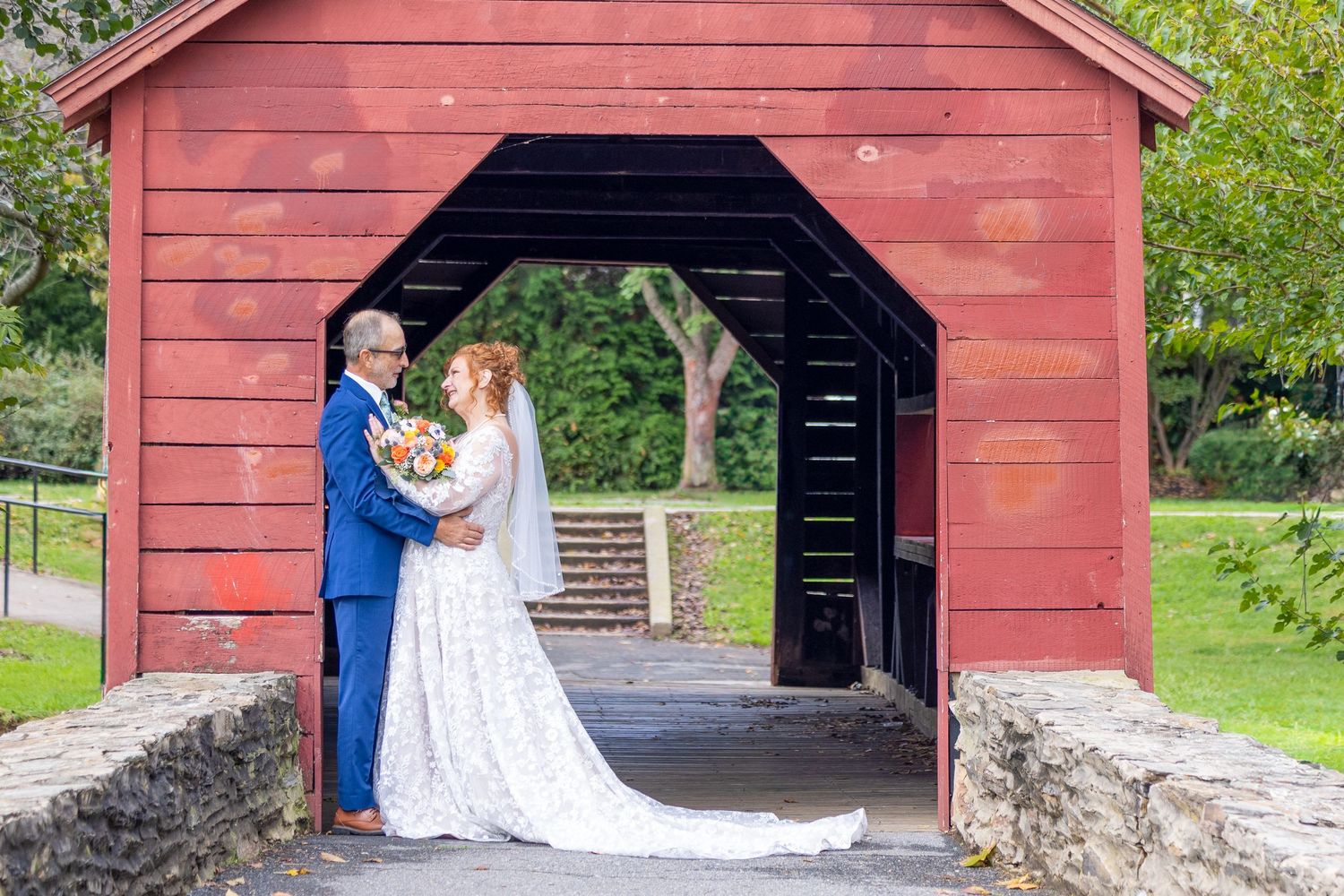 frederick county wedding photography Couple shares intimate moments under a rustic red barn overhang.