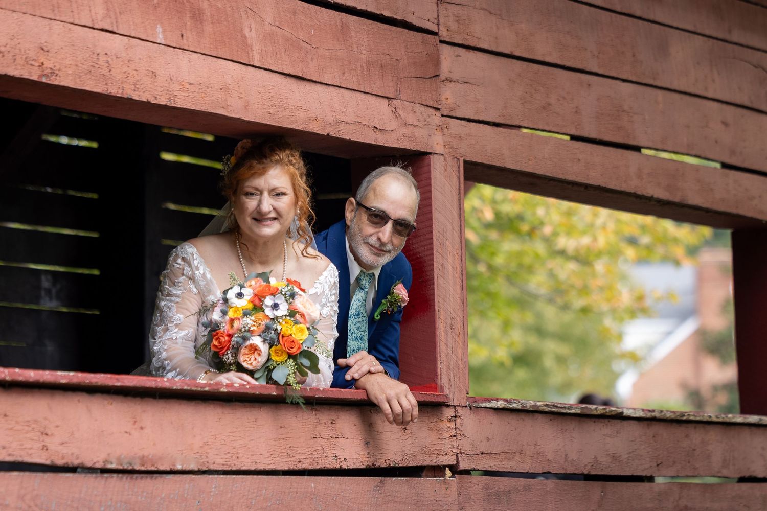 frederick county wedding photography Wedding couple peeks through rustic red barn slats for creative photo.