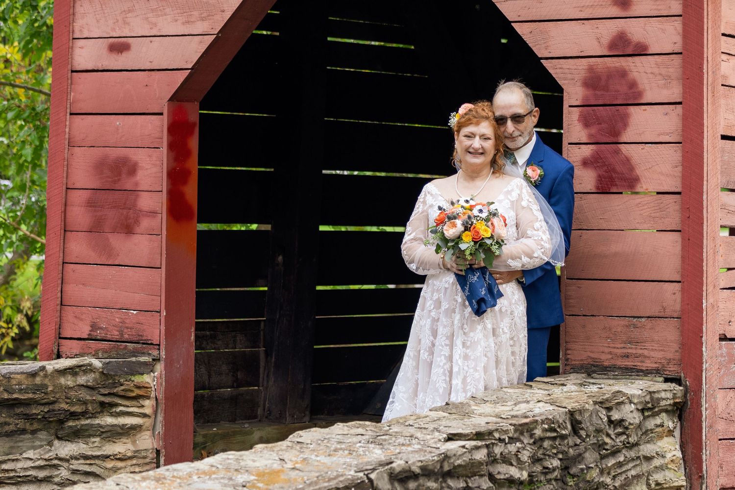 frederick county wedding photography Couple poses beneath rustic red barn overhang during outdoor wedding photoshoot.