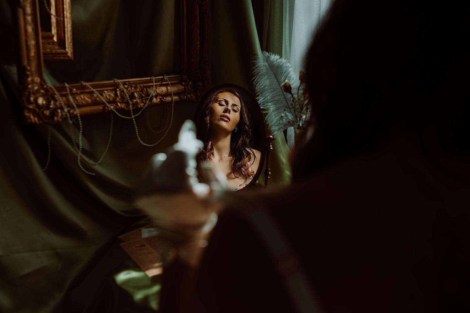 brunette sits in front of vintage oval mirror wearing blue gloves by Boudoir by KJ