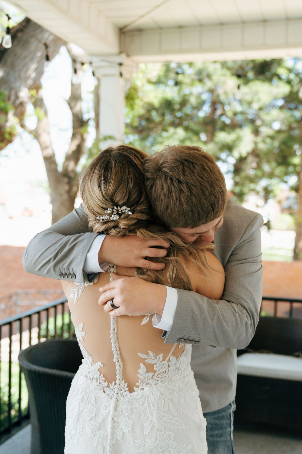 Groom embracing bride in an emotional first look moment on a porch at their wedding.