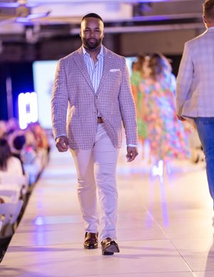 Models walk the runway in coordinated white and checkered outfits during a fashion show event.