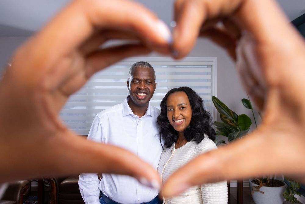 Hands forming heart shapes frame multiple romantic couple photos against a white background.