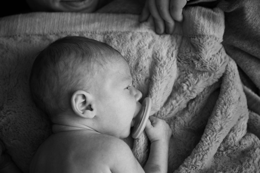 Newborn laying on belly on his mothers chest.