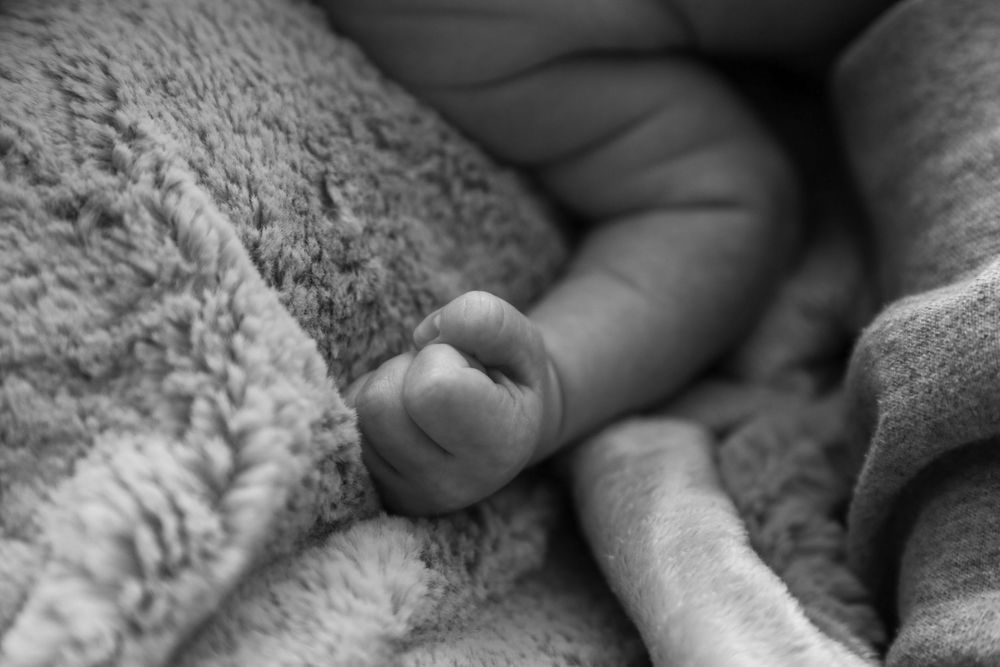 Newborn fist balled up against a blanket.