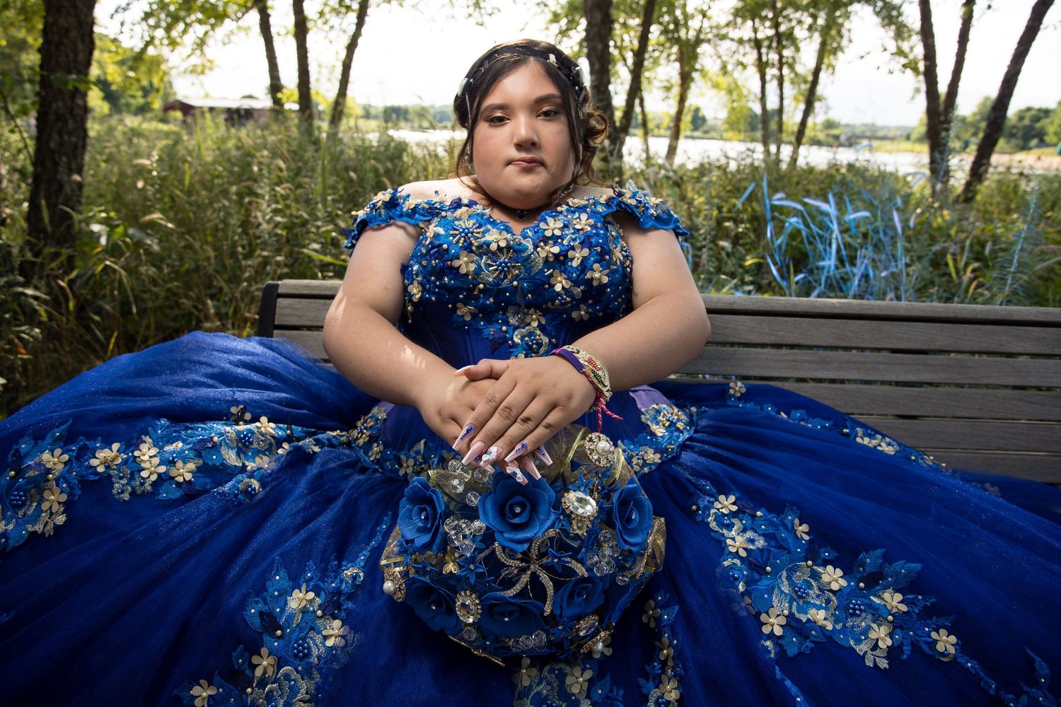Quinceañera in royal blue dress sitting on a park bench. Professional XV portraits in Lake County by Alex T Photography.