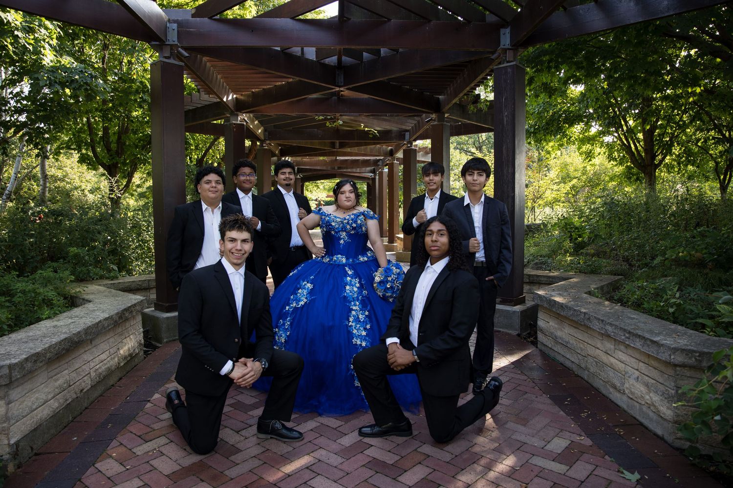 Quinceañera and chambelanes posing in a scenic outdoor walkway. Expert Lake County Quinceañera photography for Jocelyn's Mis XV by Alex T.