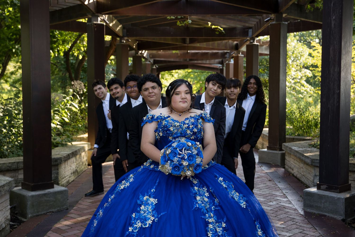 Full court of honor portrait with Quinceañera Jocelyn in a royal blue gown. Professional XV group photography at Independence Grove Park