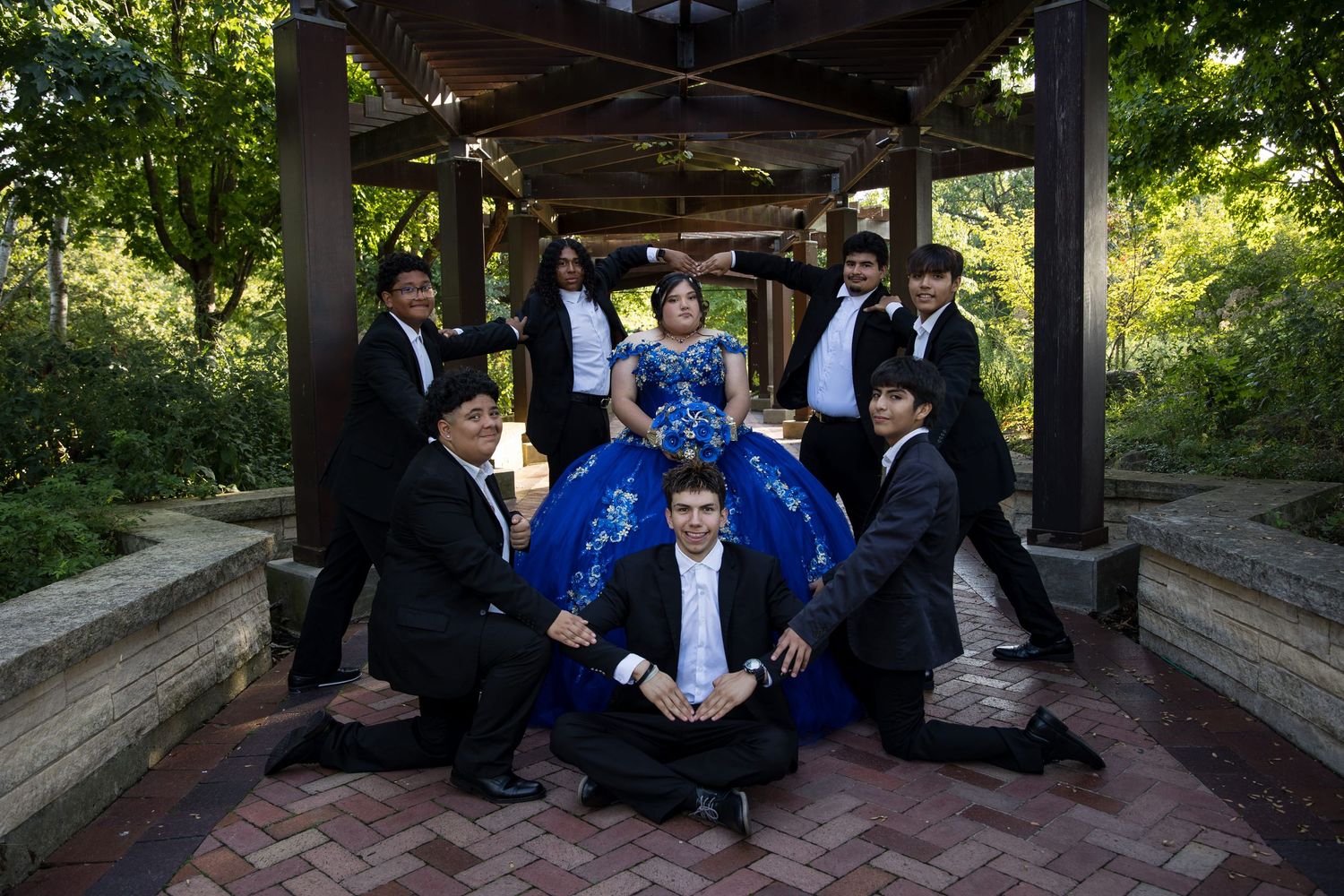 Quinceañera with court of honor posing under a wooden pergola. Royal blue XV theme photography in Lake County by Alex T Photography.
