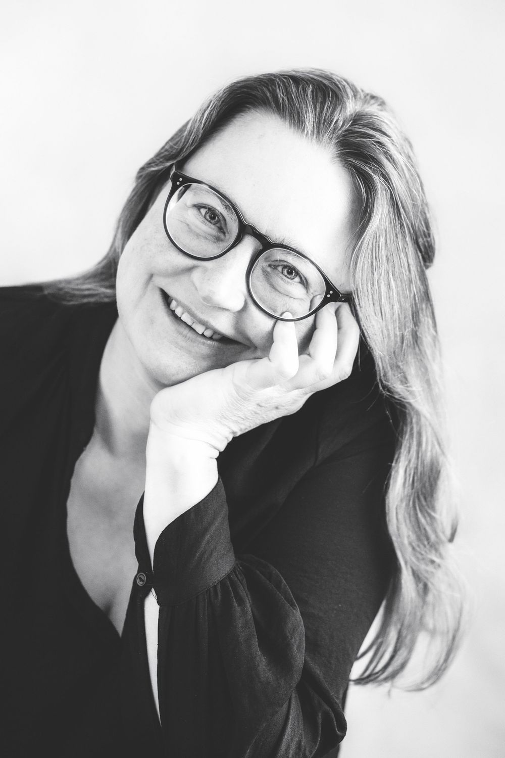 A series of black and white portraits showing someone in glasses and a dark top smiling at the camera.