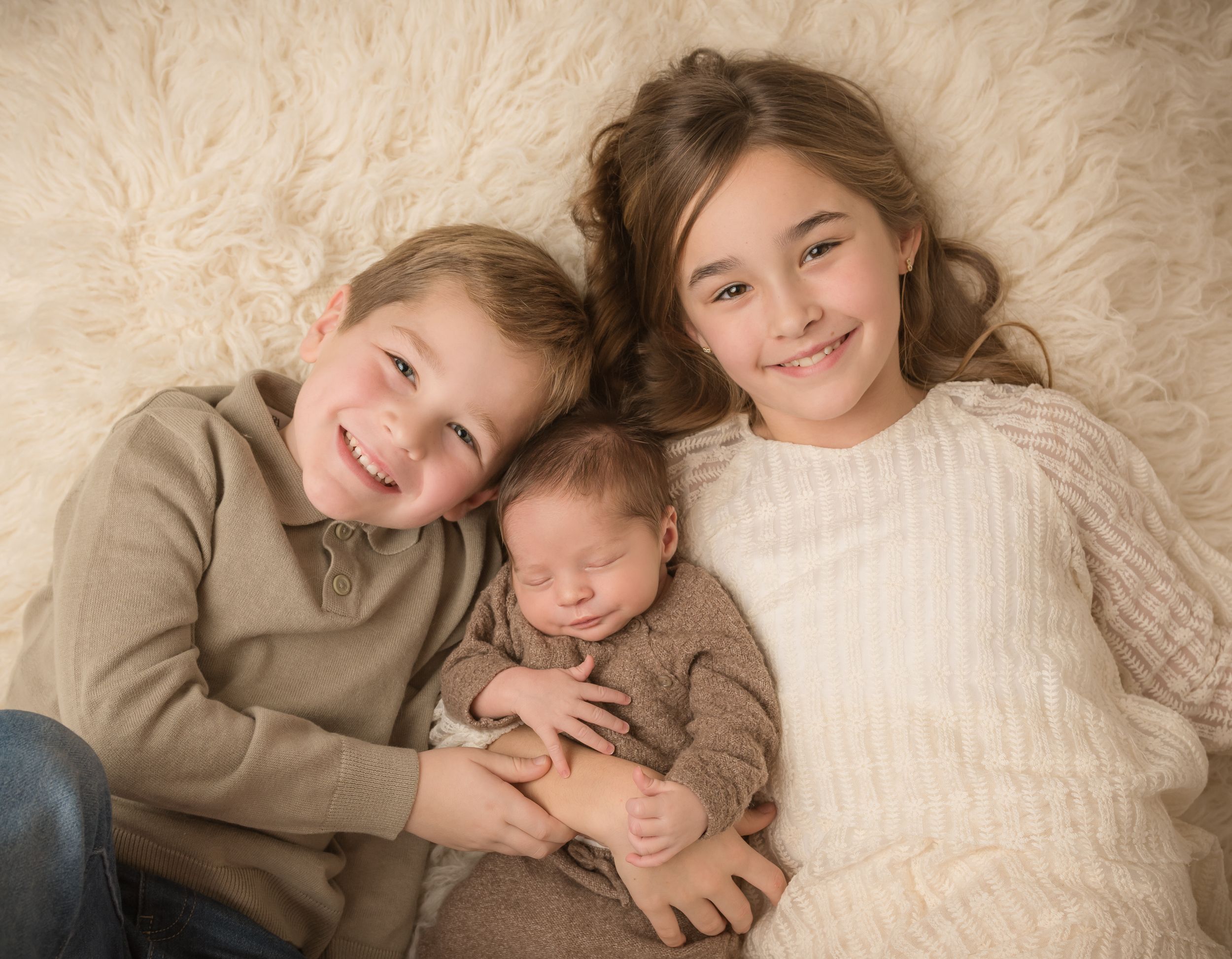 Two young children snuggling together in a series of heartwarming poses with their newborn baby brother.